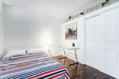 a white bedroom with a bed and a table at Magnifique appartement Montréal Centre-Ville in Montréal