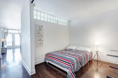 a white bedroom with a bed with a striped blanket at Magnifique appartement Montréal Centre-Ville in Montréal