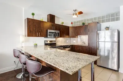 a kitchen with a counter with stools and a refrigerator at Magnifique appartement Montréal Centre-Ville in Montréal