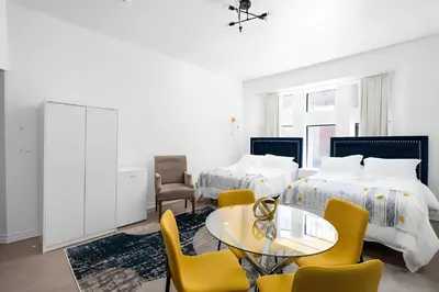 a hotel room with two beds and a table and chairs at Kozy Stays Drummond Modern apartments in Montréal