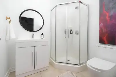 a bathroom with a shower and a toilet and a sink at Kozy Stays Drummond Modern apartments in Montréal