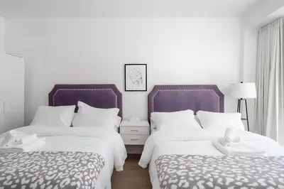 two beds in a room with white and purple at Kozy Stays Drummond Modern apartments in Montréal