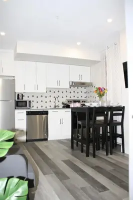 a kitchen with white cabinets and a black table and chairs at Cozy stays in Montréal