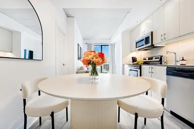 a white kitchen with a table with chairs and a vase of flowers at Charming Champs Élysées -Old Montreal-Downtown Montreal - Laundry in Montréal