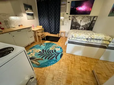 a small room with a bed and a kitchen with a rug at Montreal Hideaway in a Residential area in Montréal