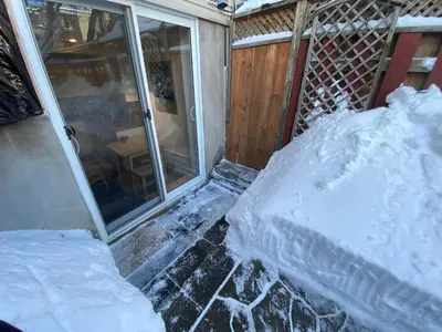 a porch covered in snow next to a sliding glass door at Montreal Hideaway in a Residential area in Montréal