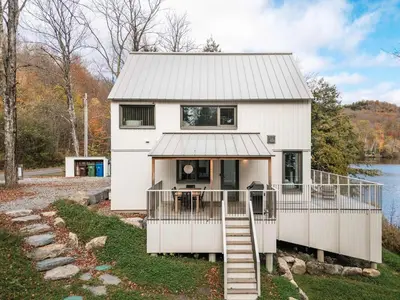 a white house with a staircase leading up to it at Wild Pond Villa in Mansonville