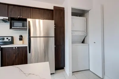 a kitchen with a stainless steel refrigerator and wooden cabinets at 2CAC rénover, tranquille, près du parc, commodités et activités in Montréal