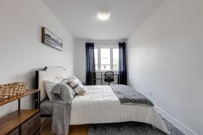 a white bedroom with a bed and a window at 2CAC rénover, tranquille, près du parc, commodités et activités in Montréal