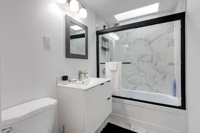 a white bathroom with a sink and a shower at 2CAC rénover, tranquille, près du parc, commodités et activités in Montréal