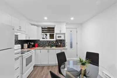 a white kitchen with a glass table and chairs at NEW LOFT -WIFI -Quiet -Tohu -Easy Transit -Park in Montréal