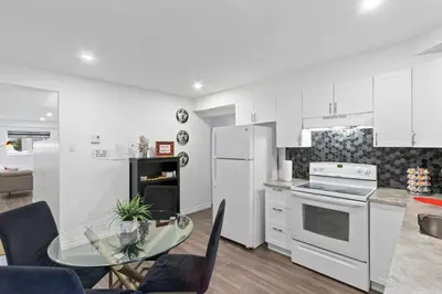 a kitchen with white cabinets and a glass table at NEW LOFT -WIFI -Quiet -Tohu -Easy Transit -Park in Montréal