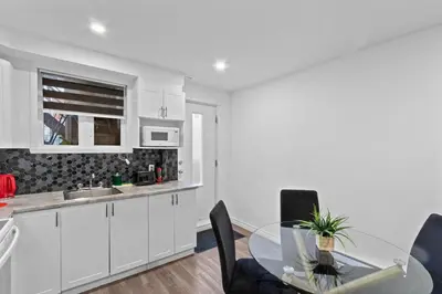 a kitchen with white cabinets and a glass table at NEW LOFT -WIFI -Quiet -Tohu -Easy Transit -Park in Montréal