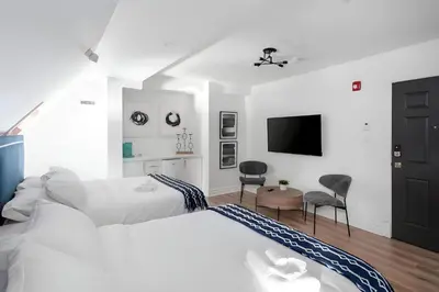 a white bedroom with a bed and a tv at Kozy Stays Penfield - Modern Rooms Heart of downtown in Montréal
