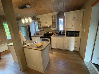 a kitchen with white cabinets and a island in it at Beautiful cottage waterfront in Trois-Lacs