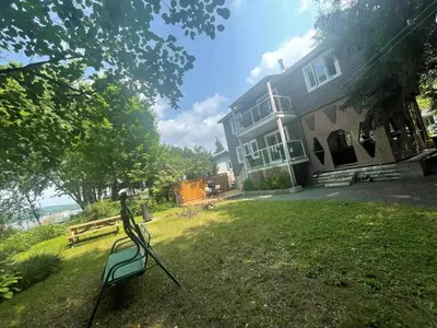 a house with a bench in the grass in front of it at Beautiful cottage waterfront in Trois-Lacs