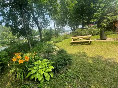 a wooden bench sitting in a park with flowers at Beautiful cottage waterfront in Trois-Lacs