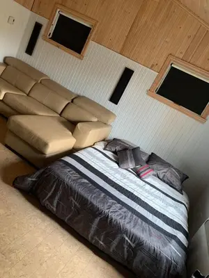 a bed and a couch in a room with windows at Beautiful cottage waterfront in Trois-Lacs