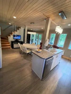 a kitchen and living room with a sink and a table at Beautiful cottage waterfront in Trois-Lacs