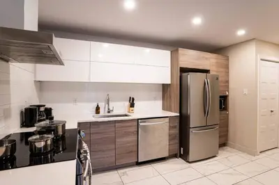 a kitchen with a stainless steel refrigerator and cabinets at 204 - Modern Cozy Suite with 2BR, Gym, Parking, DT & Airport in Montréal