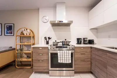 a kitchen with a stove top oven in a room at 204 - Modern Cozy Suite with 2BR, Gym, Parking, DT & Airport in Montréal