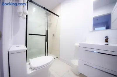 a white bathroom with a toilet and a glass shower at 103 - Bright Modern 2BR, Near DT W Street Parking in Montréal