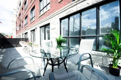 a patio with a glass table and white chairs at 103 - Bright Modern 2BR, Near DT W Street Parking in Montréal