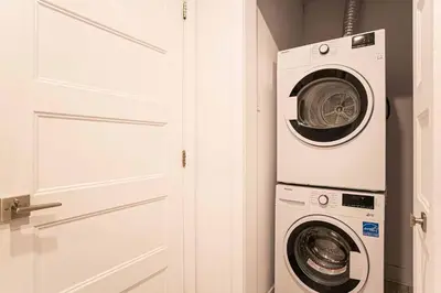 a laundry room with a washer and dryer next to a door at 107 - Sleek New 2BR Apt with Patio, Parking, DT&Airport in Montréal