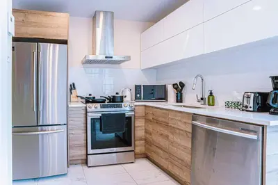 a kitchen with stainless steel appliances and wooden cabinets at 112 - Spacious 1BR Getaway, Gym, Paid Parking in Montréal