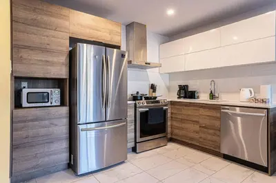 a kitchen with stainless steel appliances and wooden cabinets at 117 - Spacious 2 King BD with Parking, Near DT & Airport in Montréal