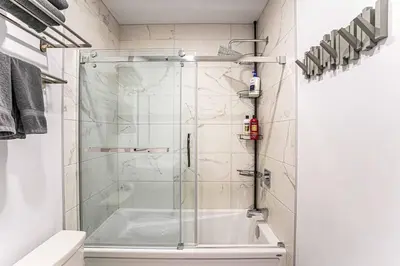 a shower with a glass door in a bathroom at 119 - Vibrant Chic Designer 2BR with Gym,Parking,Airport&DT in Montréal