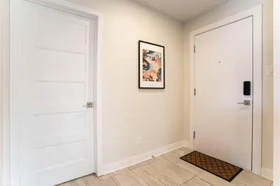 a hallway with a white door and a picture on the wall at 201 - Comfy Spacious 2BR Apt with Gym, Parking, DT&Airport in Montréal