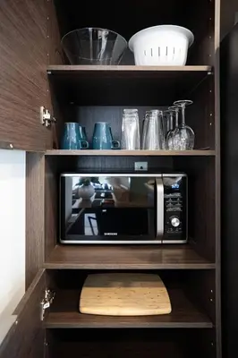 a microwave in a wooden shelf with other kitchen items at 201 - Comfy Spacious 2BR Apt with Gym, Parking, DT&Airport in Montréal
