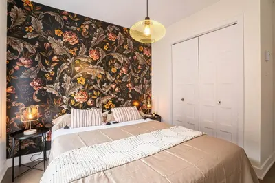 a bedroom with a large bed with a floral wallpaper at 201 - Comfy Spacious 2BR Apt with Gym, Parking, DT&Airport in Montréal