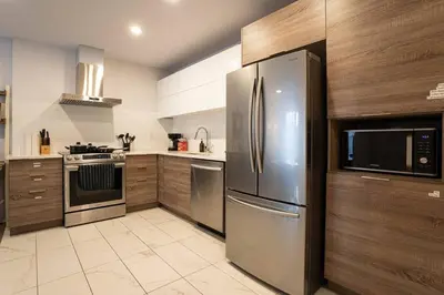 a kitchen with stainless steel appliances and wooden cabinets at 202 - Modern Exquisite Suite with Gym,Parking, near DT&Airport in Montréal