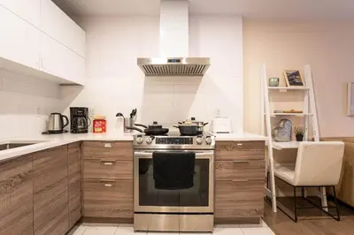 a kitchen with a stove top oven next to a counter at 203 - Fantastic Cozy New 2 Queen Condo with Gym, DT&Airport in Montréal