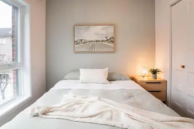 a white bedroom with a bed and a window at 203 - Fantastic Cozy New 2 Queen Condo with Gym, DT&Airport in Montréal