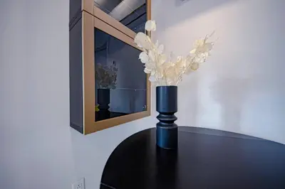 a black table with a vase with white flowers on it at 208 - Modern Cozy Bright Apt with 2BR,Gym,Prking,DT&Airport in Montréal