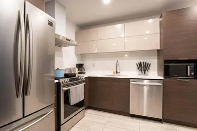 a kitchen with stainless steel appliances and wooden cabinets at 209 - Modern Home Ambiance 2 BR with Gym,Parking,DT&Airport in Montréal