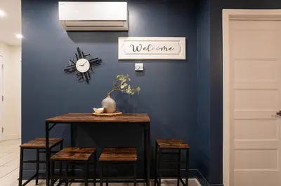 a blue wall with a table and stools and a clock at 209 - Modern Home Ambiance 2 BR with Gym,Parking,DT&Airport in Montréal