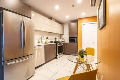 a kitchen with a stainless steel refrigerator and a glass table at 211 - Cozy New Condo with 2 Queens, Parking, DT&Airport in Montréal