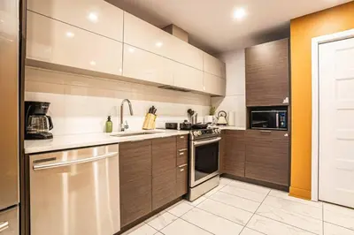 a kitchen with brown cabinets and a sink and a stove at 211 - Cozy New Condo with 2 Queens, Parking, DT&Airport in Montréal