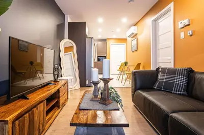 a living room with a couch and a flat screen tv at 211 - Cozy New Condo with 2 Queens, Parking, DT&Airport in Montréal