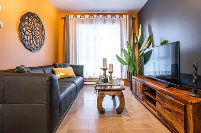 a living room with a black couch and a television at 211 - Cozy New Condo with 2 Queens, Parking, DT&Airport in Montréal