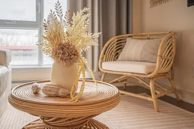 a wicker table with a vase with flowers and a chair at 217 - Pastel Stylist 2 KING-BR with Parking, nr DT&Airport in Montréal