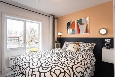 a bedroom with a black and white bed and a window at 219 - Abstract Designer King Suite with Parking, DT&Airport in Montréal