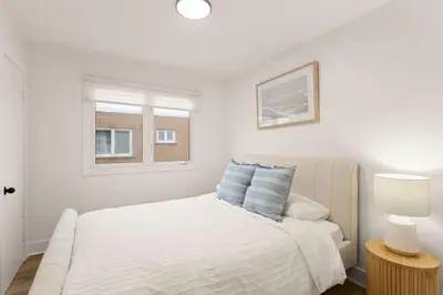 a white bedroom with a bed and a window at The Samson Haven in Laval