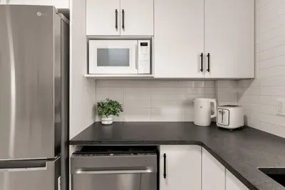 a kitchen with white cabinets and a stainless steel refrigerator at The Samson Haven in Laval