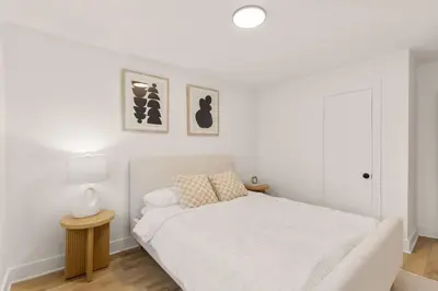 a white bedroom with a bed and two pictures on the wall at The Samson Haven in Laval