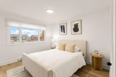 a white bedroom with a bed and a window at The Samson Haven in Laval